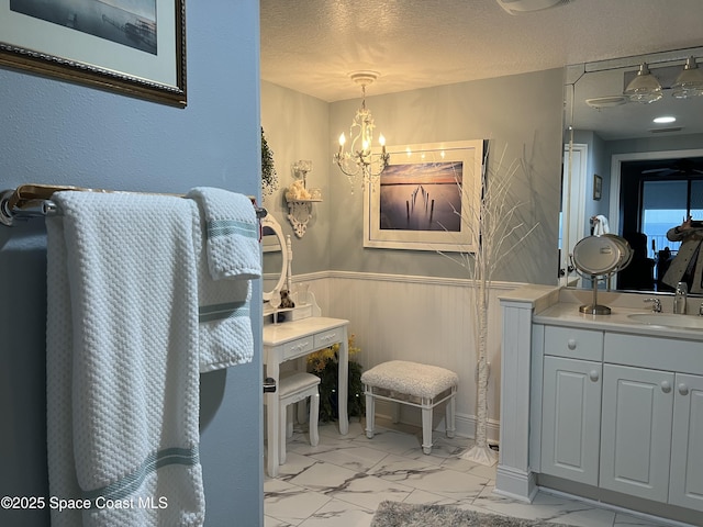 bathroom featuring ceiling fan with notable chandelier, vanity, a textured ceiling, and wooden walls