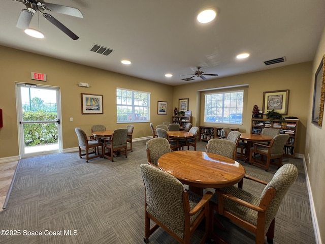 carpeted dining area with ceiling fan and plenty of natural light