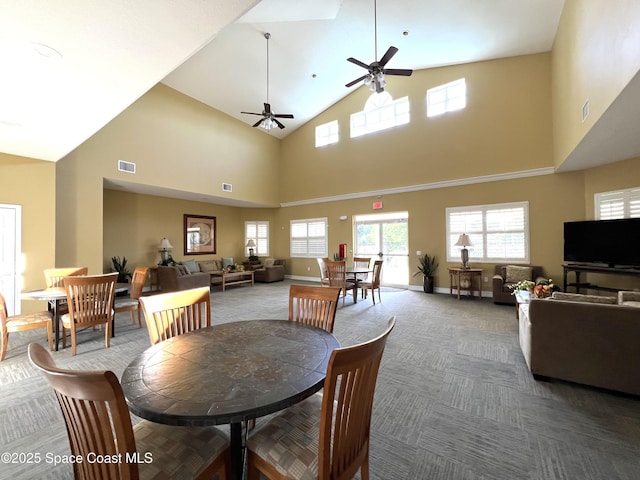 carpeted dining area with ceiling fan and a high ceiling