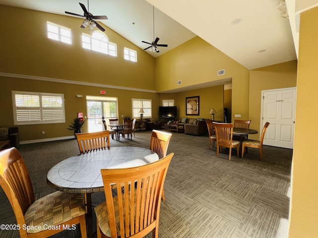 dining space featuring ceiling fan, carpet floors, and a high ceiling