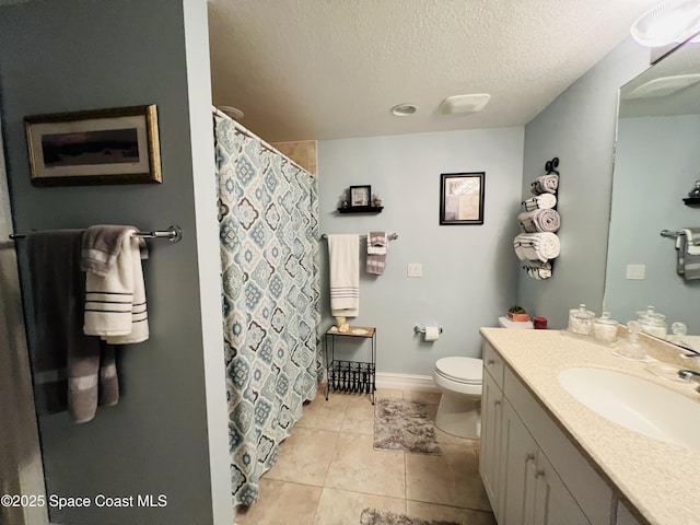 bathroom with tile patterned floors, vanity, a textured ceiling, and toilet