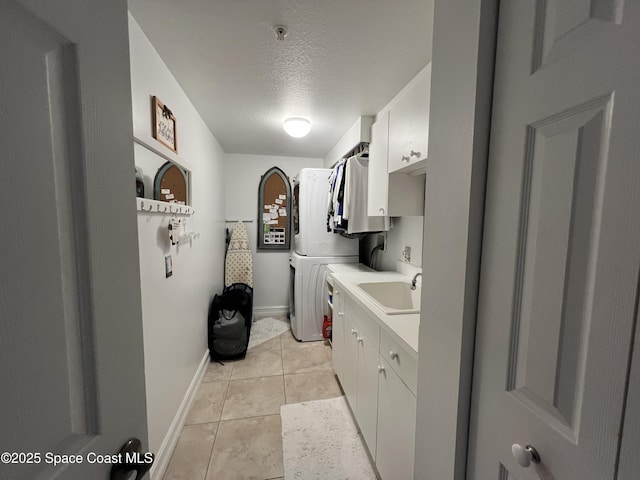 laundry area with cabinets, a textured ceiling, sink, light tile patterned floors, and washer / clothes dryer