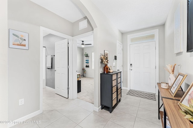 foyer entrance featuring ceiling fan, light tile patterned floors, and a textured ceiling