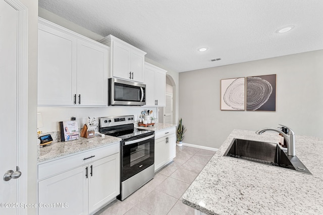 kitchen featuring white cabinets, sink, light stone countertops, light tile patterned floors, and stainless steel appliances