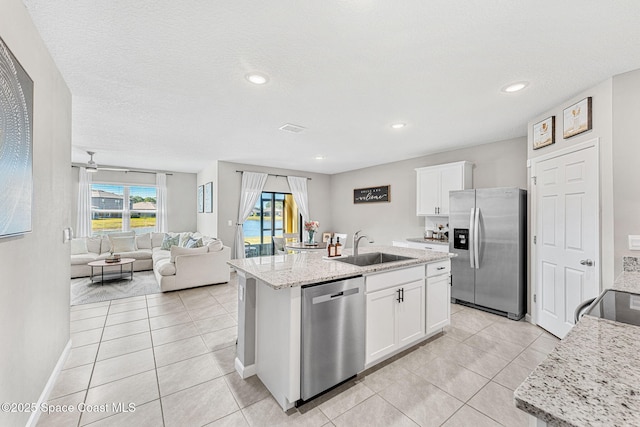 kitchen with stainless steel appliances, white cabinetry, a center island with sink, and sink