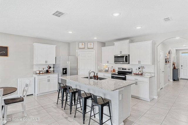 kitchen featuring white cabinets, appliances with stainless steel finishes, an island with sink, and sink