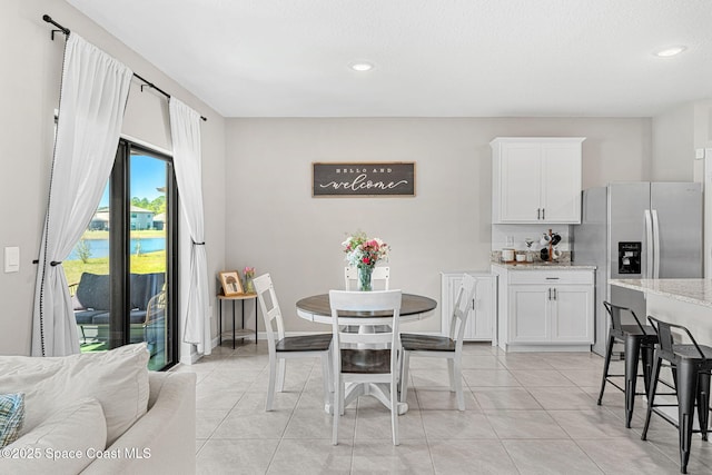 dining room with a water view and light tile patterned flooring