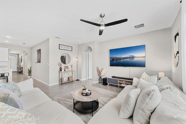 living room with ceiling fan, light tile patterned floors, and a textured ceiling