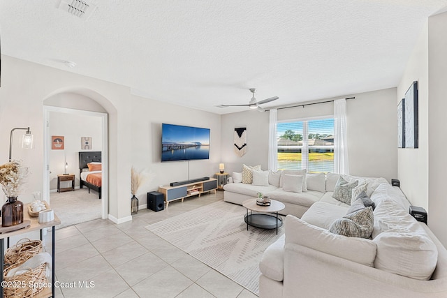 living room with light tile patterned floors, a textured ceiling, and ceiling fan