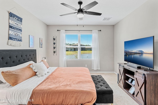 bedroom with a textured ceiling, light colored carpet, and ceiling fan