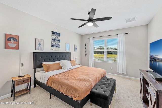 bedroom with ceiling fan, light carpet, and a textured ceiling