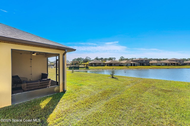 view of yard featuring ceiling fan and a water view