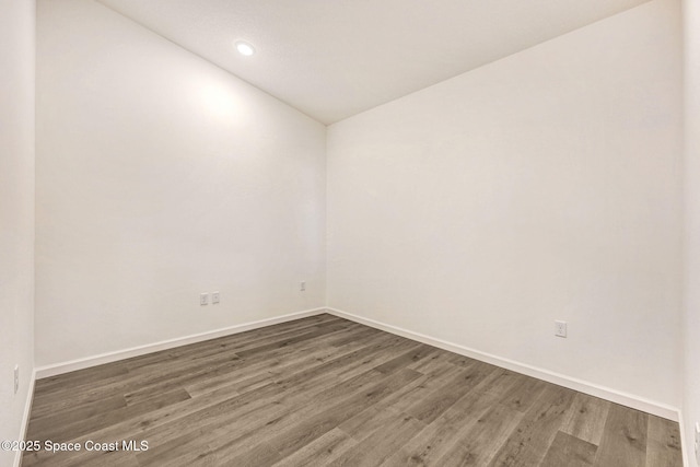 unfurnished room featuring dark hardwood / wood-style floors and lofted ceiling