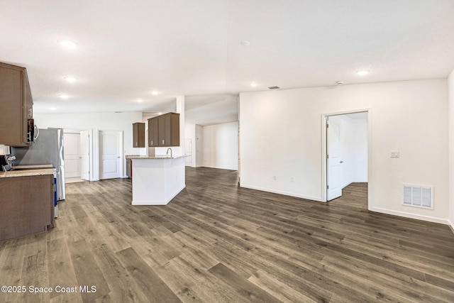 kitchen with a kitchen island, stove, dark wood-type flooring, and vaulted ceiling