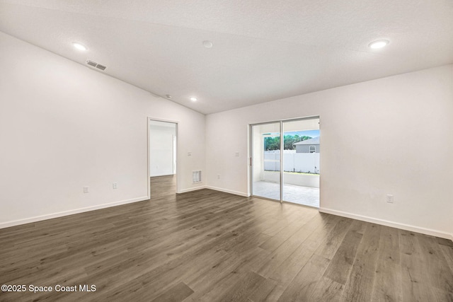 unfurnished room featuring a textured ceiling, dark hardwood / wood-style floors, and lofted ceiling