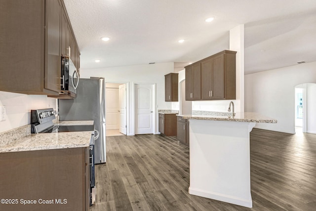 kitchen with sink, light stone countertops, dark hardwood / wood-style flooring, kitchen peninsula, and stainless steel appliances