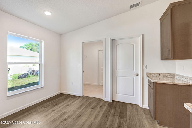 unfurnished dining area with a textured ceiling, hardwood / wood-style floors, and lofted ceiling