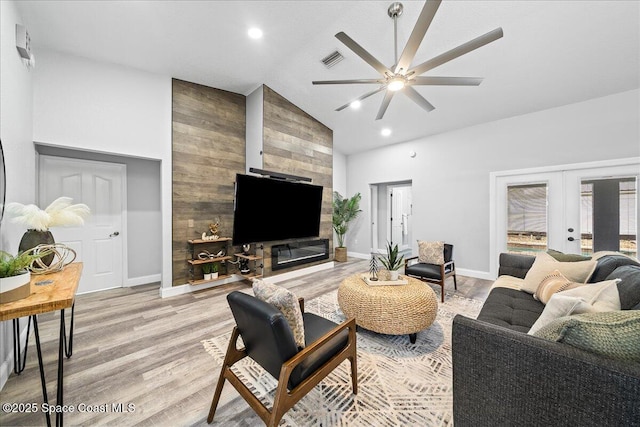 living room featuring ceiling fan, light wood-type flooring, lofted ceiling, and french doors