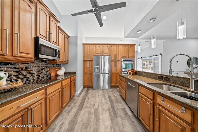 kitchen with hanging light fixtures, dark stone countertops, sink, and stainless steel appliances