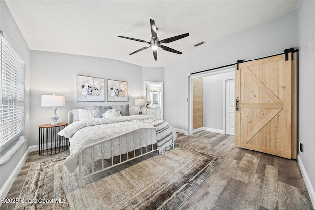 bedroom with hardwood / wood-style floors, a barn door, a textured ceiling, and ceiling fan