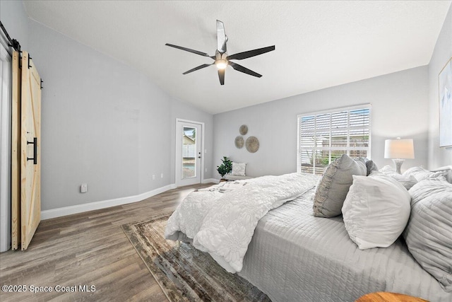 bedroom with a barn door, ceiling fan, lofted ceiling, and hardwood / wood-style flooring