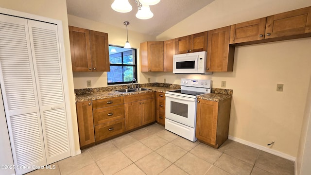 kitchen with sink, white appliances, light tile patterned floors, decorative light fixtures, and vaulted ceiling