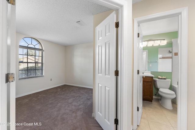 hall with light carpet and a textured ceiling