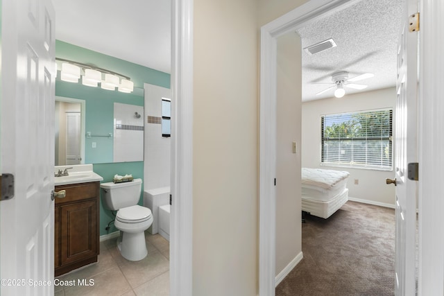 bathroom featuring vanity, ceiling fan, walk in shower, toilet, and a textured ceiling