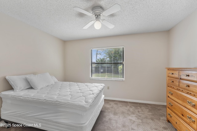 carpeted bedroom featuring ceiling fan and a textured ceiling