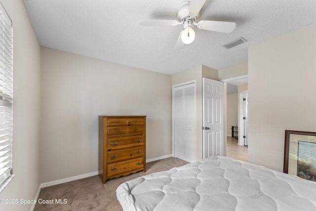 carpeted bedroom featuring multiple windows, a textured ceiling, a closet, and ceiling fan