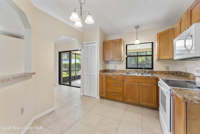 kitchen featuring hanging light fixtures, plenty of natural light, sink, and white appliances