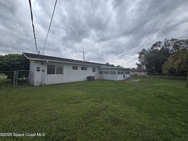 rear view of property featuring central AC unit and a yard