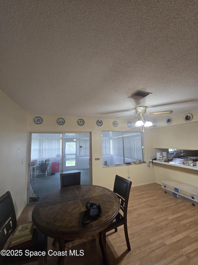 dining room with a textured ceiling, ceiling fan, and light hardwood / wood-style floors