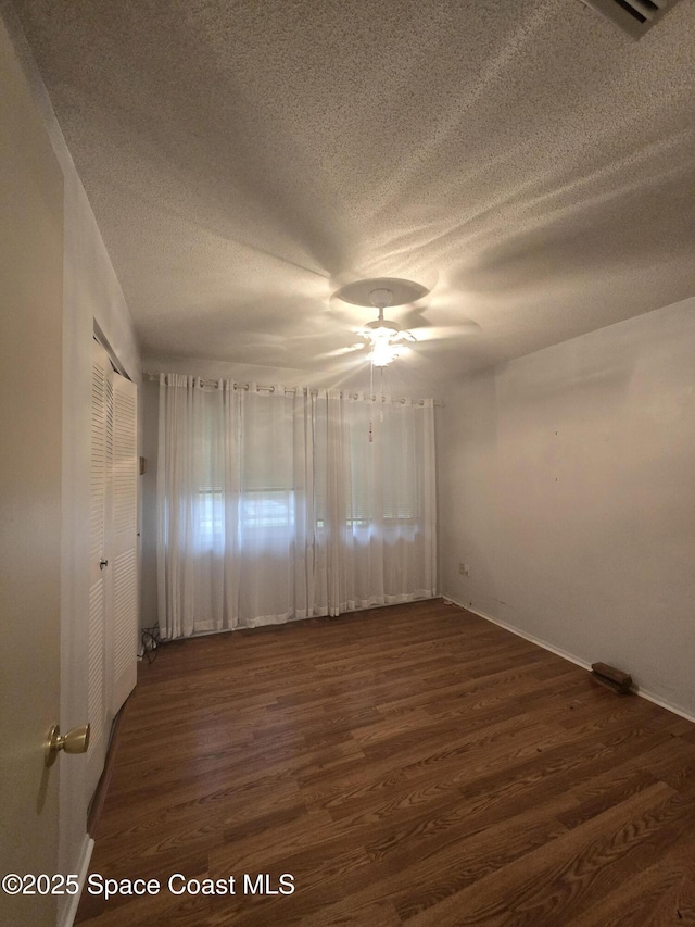 unfurnished room featuring a textured ceiling, ceiling fan, and dark hardwood / wood-style floors