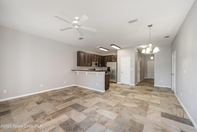 kitchen with appliances with stainless steel finishes, decorative light fixtures, a kitchen bar, kitchen peninsula, and dark brown cabinets