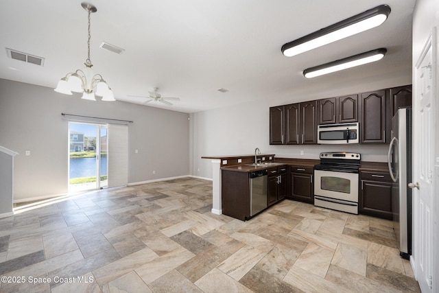 kitchen with sink, appliances with stainless steel finishes, dark brown cabinets, a water view, and decorative light fixtures