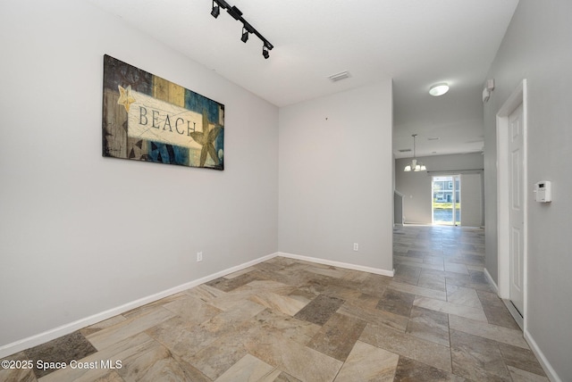 unfurnished room with an inviting chandelier and track lighting