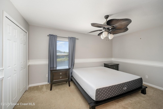 bedroom featuring ceiling fan, light colored carpet, and a closet