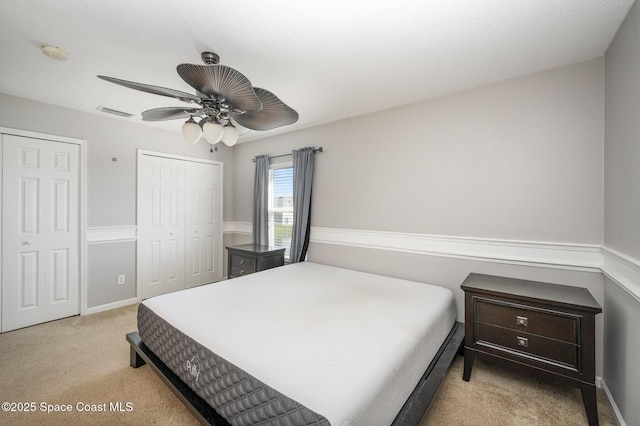 carpeted bedroom with multiple closets and ceiling fan