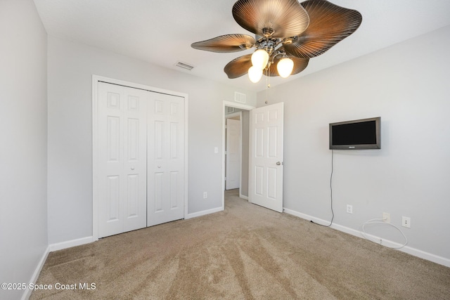 unfurnished bedroom with ceiling fan, light carpet, and a closet