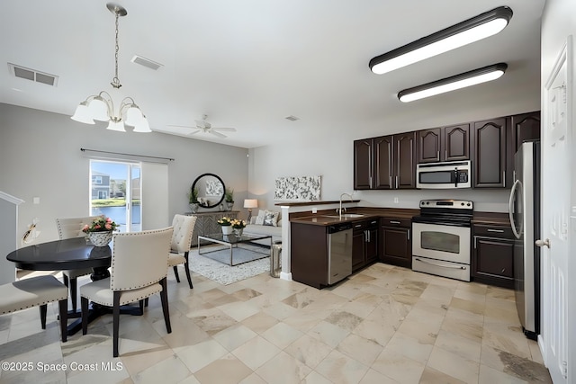 kitchen with pendant lighting, sink, appliances with stainless steel finishes, an inviting chandelier, and dark brown cabinets