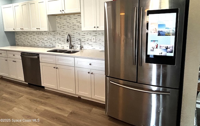 kitchen featuring sink, decorative backsplash, appliances with stainless steel finishes, dark hardwood / wood-style flooring, and white cabinetry