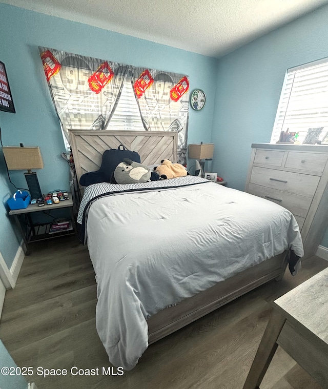 bedroom featuring hardwood / wood-style flooring, a textured ceiling, and multiple windows