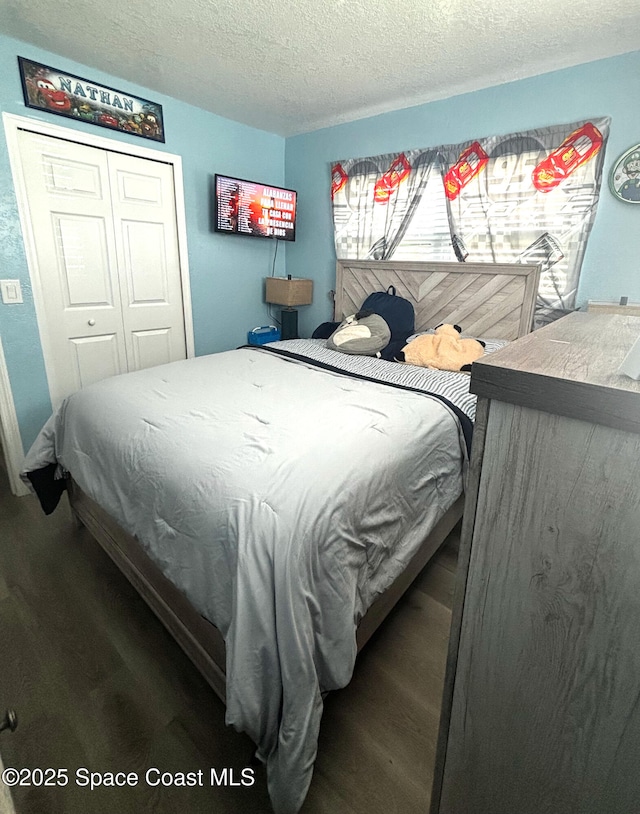 bedroom with hardwood / wood-style floors, a textured ceiling, and a closet