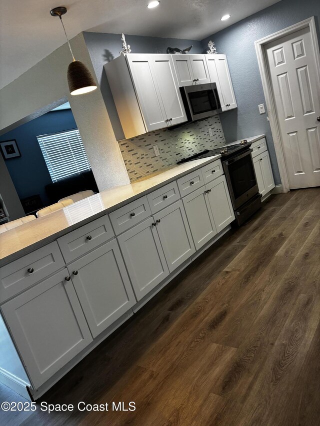 kitchen with white cabinets, hanging light fixtures, dark hardwood / wood-style floors, tasteful backsplash, and kitchen peninsula