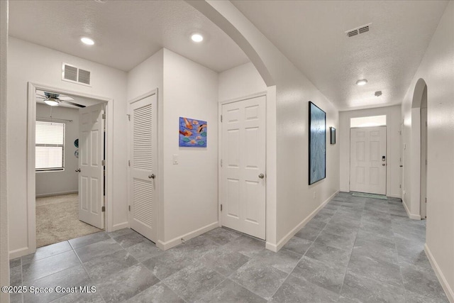 hallway featuring light colored carpet and a textured ceiling