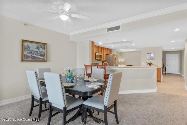 carpeted dining space with crown molding and ceiling fan