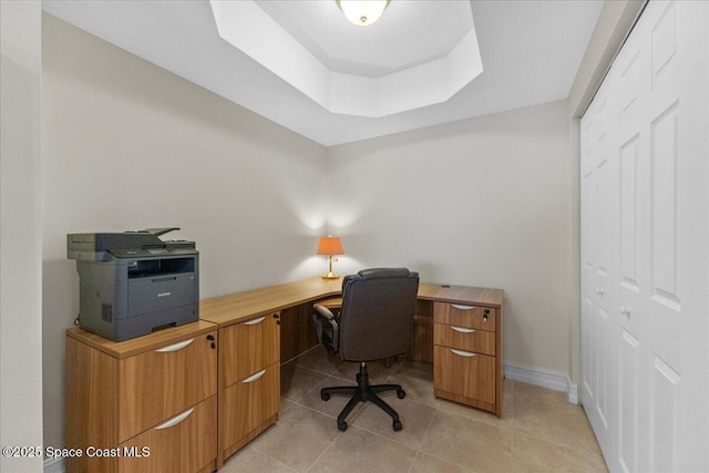 office space with a raised ceiling and light tile patterned floors