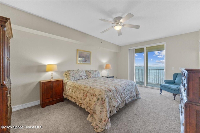 bedroom with a water view, light carpet, access to exterior, and ceiling fan