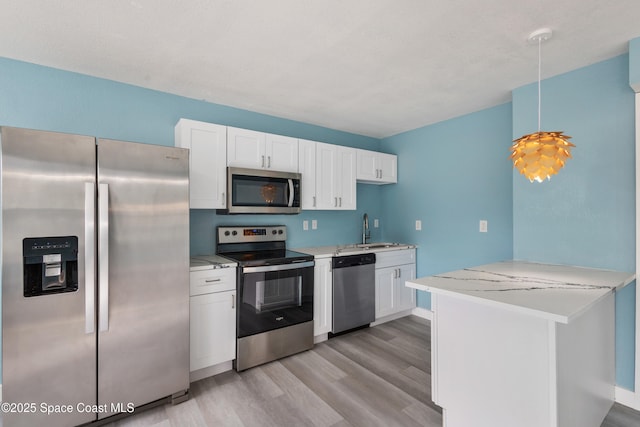 kitchen with sink, kitchen peninsula, decorative light fixtures, white cabinetry, and stainless steel appliances